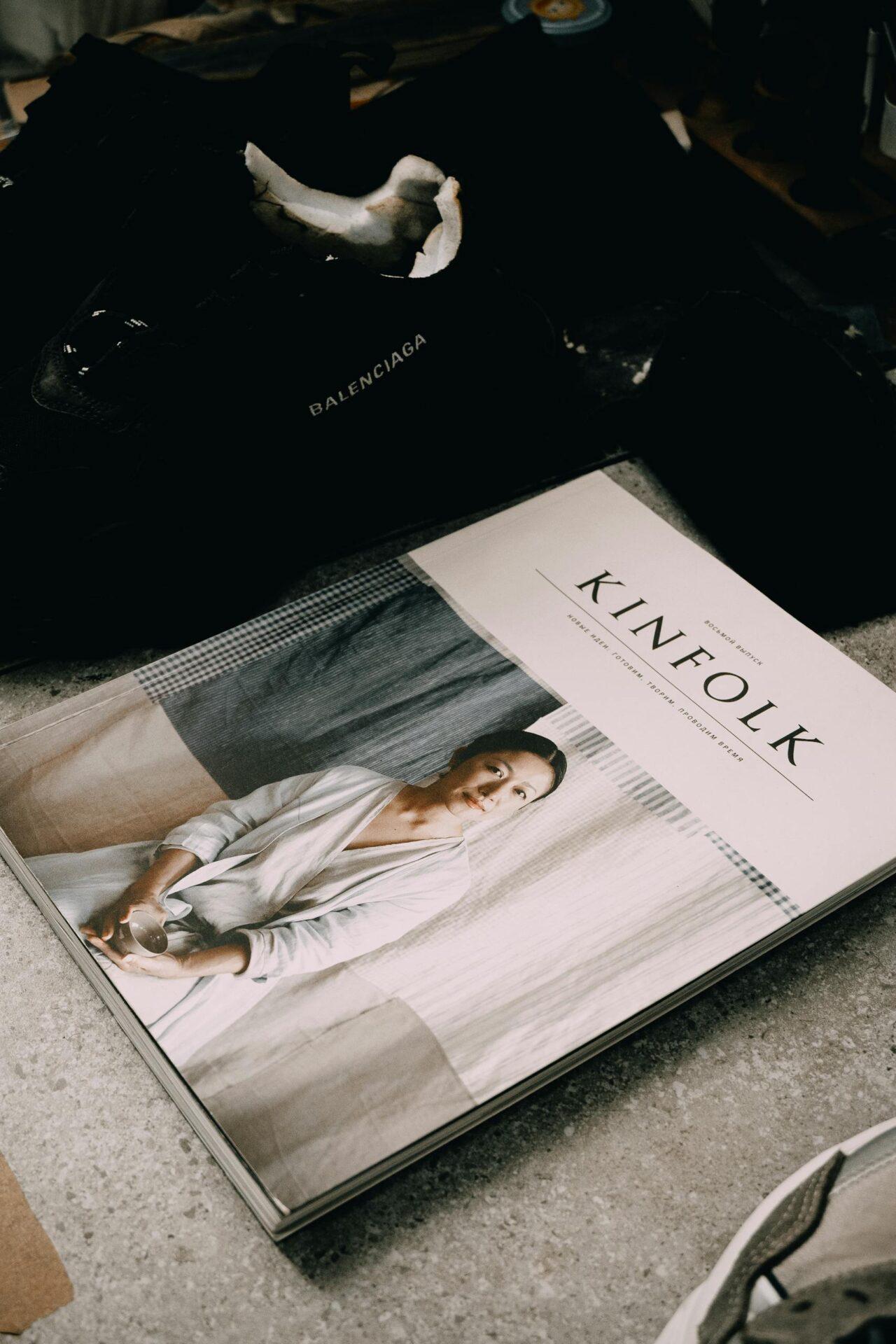 A fashionable setup featuring a Kinfolk magazine and Balenciaga sneakers on a gray surface.